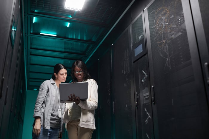 two-women-work-with-laptop-in-server-room-2026-01-08-07-07-42-utc (1) (1)